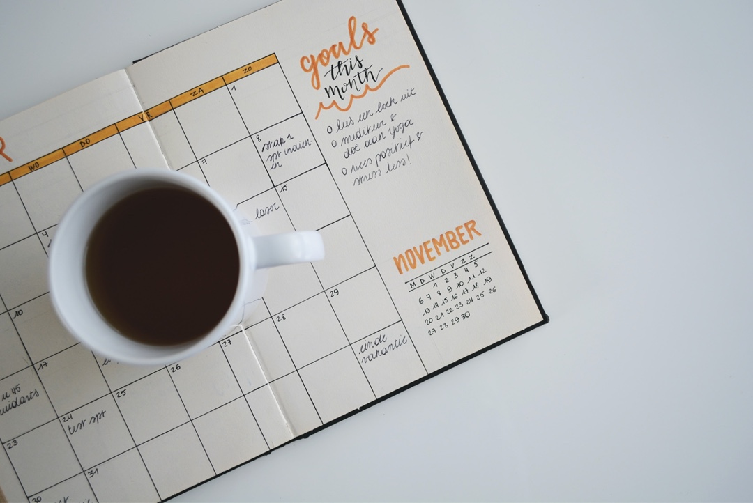 Une tasse à café posée sur un agenda, bien s'organiser pendant son télétravail